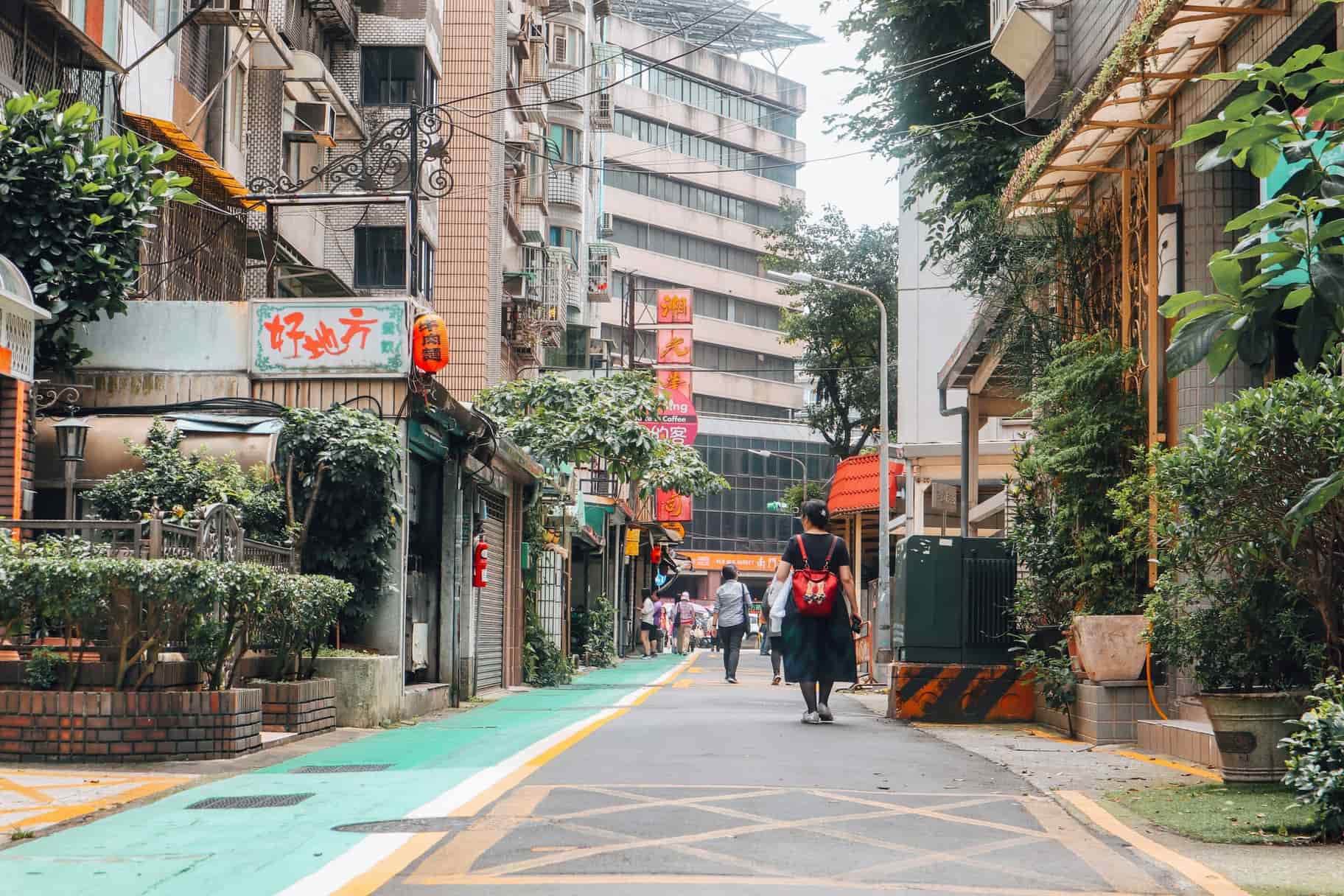 People walking along a leafy neighborhood street in Taipei